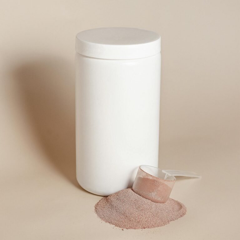 White container with protein powder and scoop on beige background.